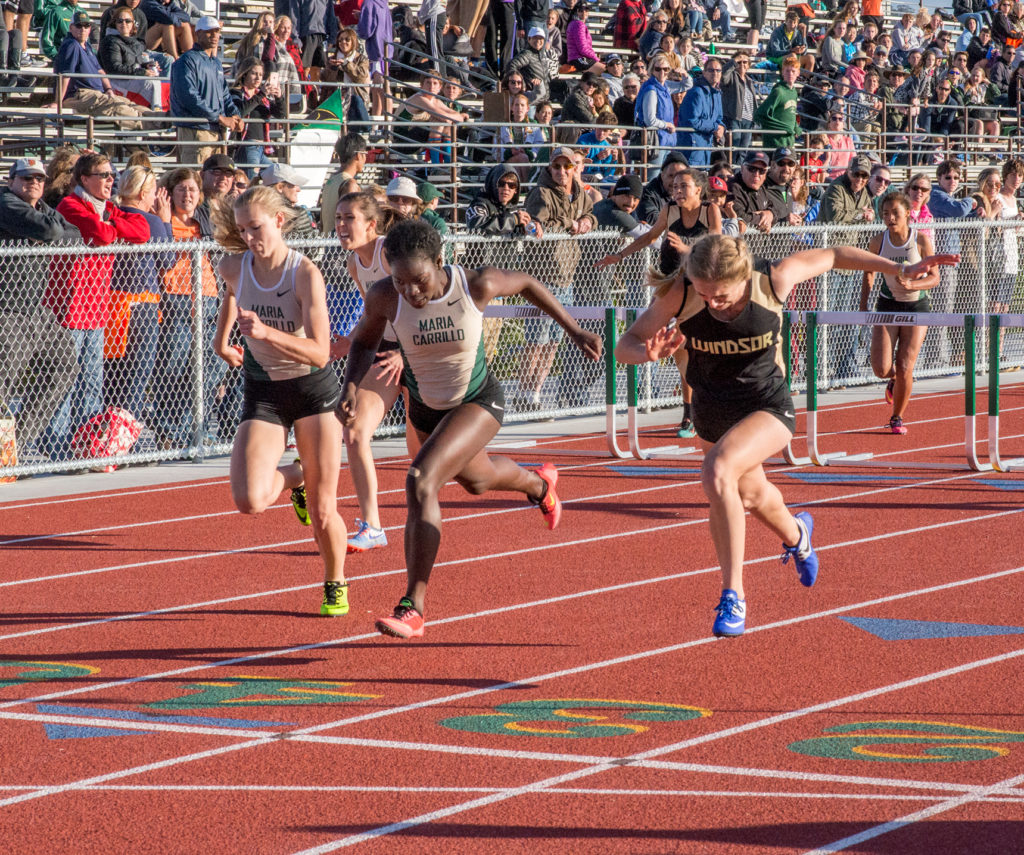 Athlete prepares for pole vault on a track with others watching.