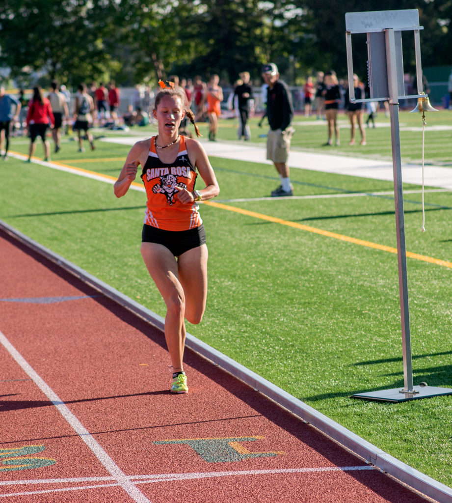 Athlete prepares for pole vault on a track with others watching.