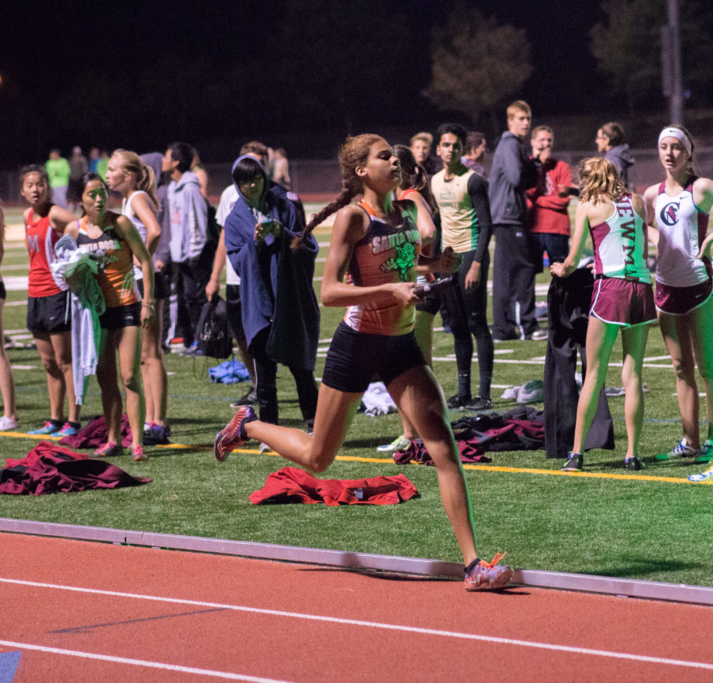Athlete prepares for pole vault on a track with others watching.