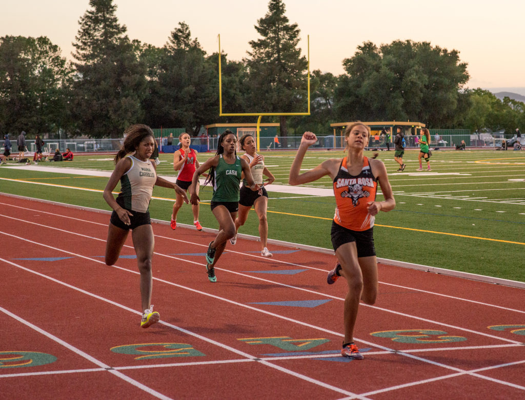 Athlete prepares for pole vault on a track with others watching.