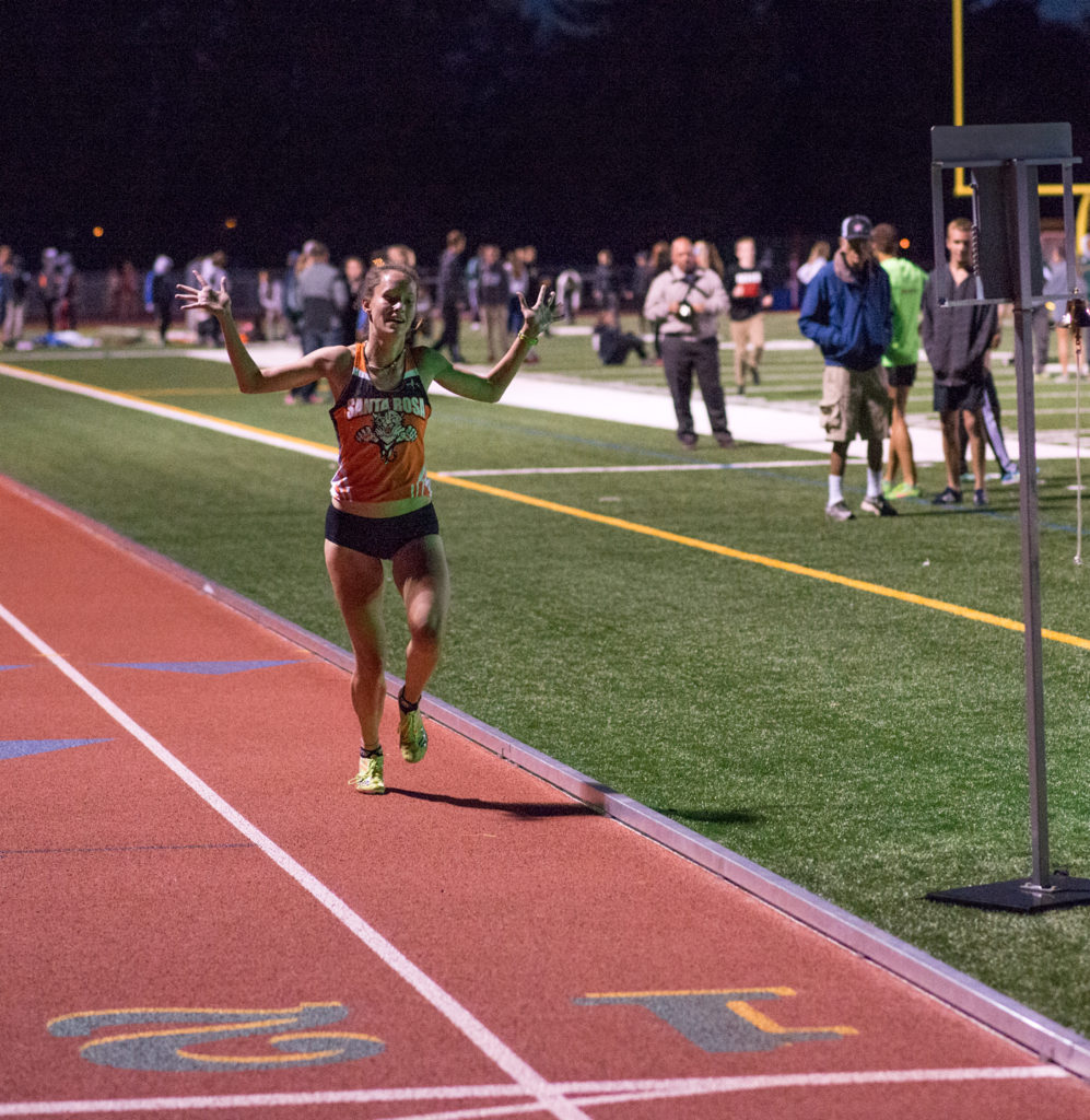 Athlete prepares for pole vault on a track with others watching.