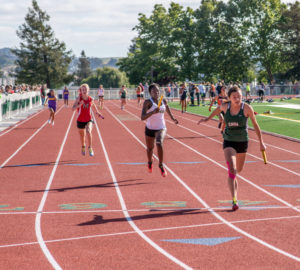 Athlete prepares for pole vault on a track with others watching.