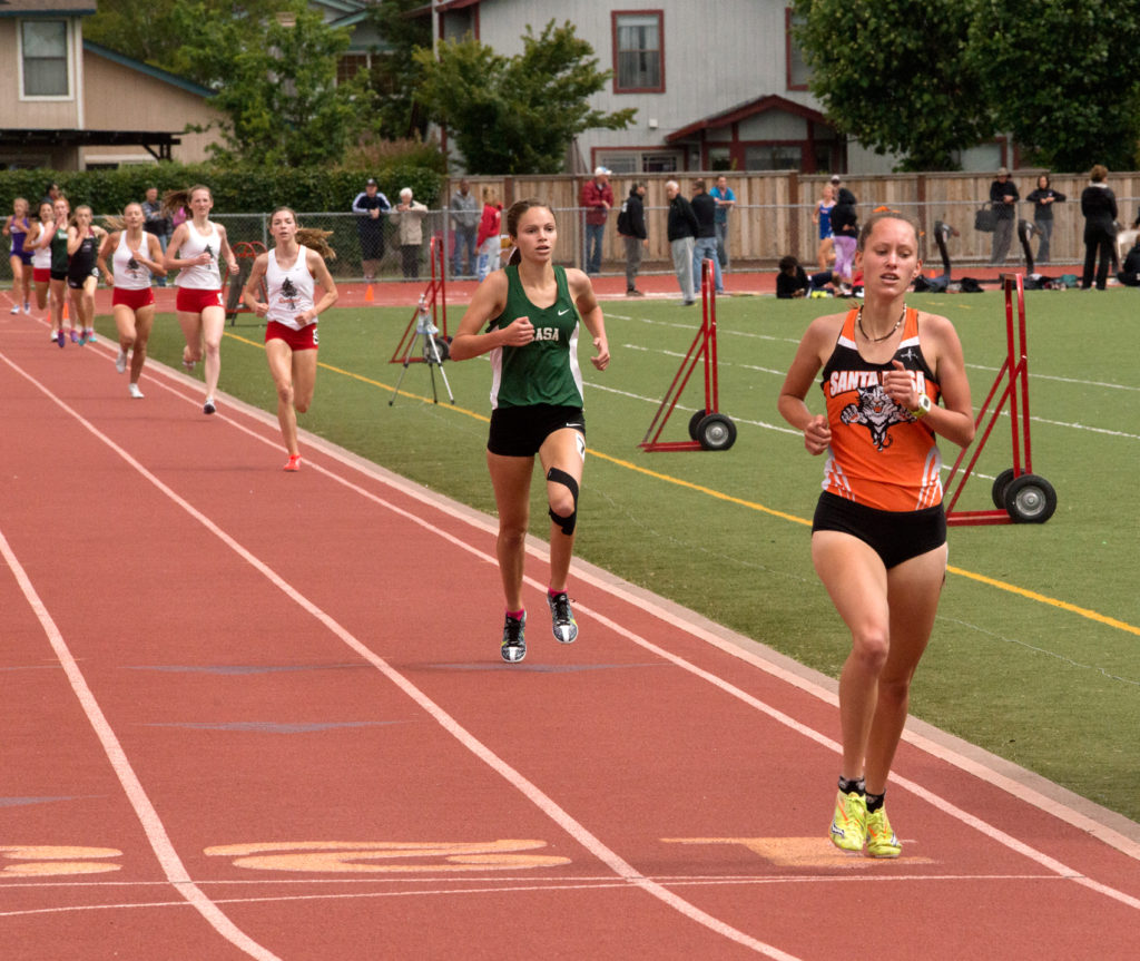 Athlete prepares for pole vault on a track with others watching.