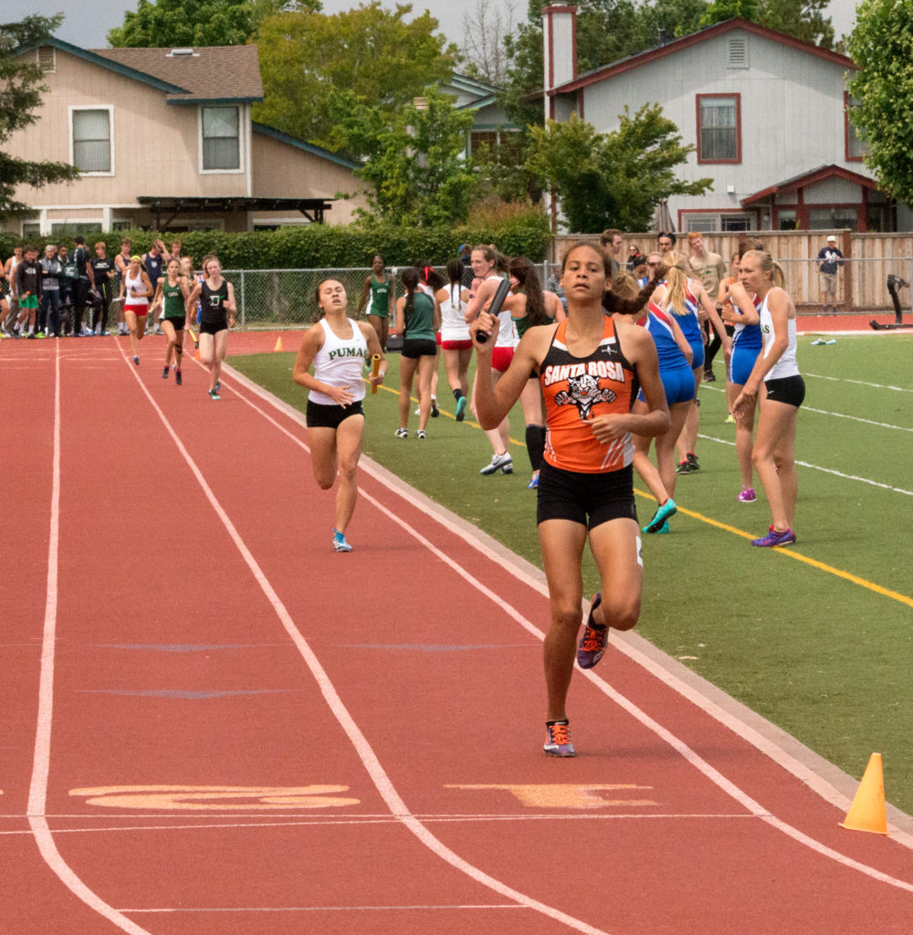 Athlete prepares for pole vault on a track with others watching.