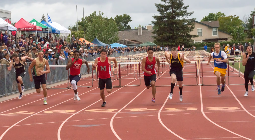 Athlete prepares for pole vault on a track with others watching.