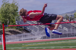 Athlete prepares for pole vault on a track with others watching.