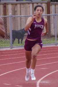 Athlete prepares for pole vault on a track with others watching.