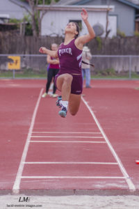 Athlete prepares for pole vault on a track with others watching.