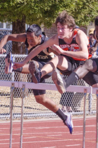 Athlete prepares for pole vault on a track with others watching.
