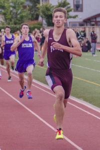 Athlete prepares for pole vault on a track with others watching.