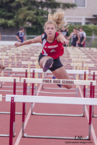 Athlete prepares for pole vault on a track with others watching.