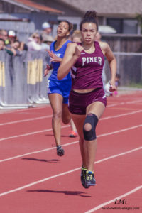 Athlete prepares for pole vault on a track with others watching.