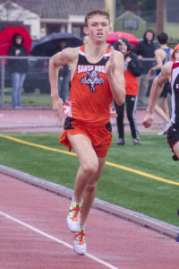 Athlete prepares for pole vault on a track with others watching.
