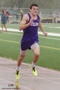 Athlete prepares for pole vault on a track with others watching.