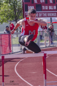 Athlete prepares for pole vault on a track with others watching.