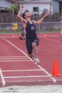 Athlete prepares for pole vault on a track with others watching.