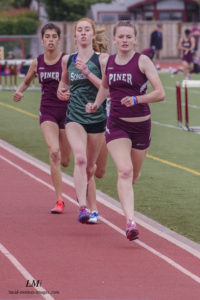 Athlete prepares for pole vault on a track with others watching.