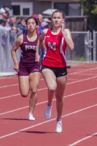 Athlete prepares for pole vault on a track with others watching.