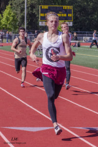 Athlete prepares for pole vault on a track with others watching.