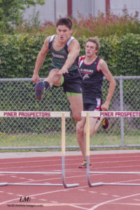 Athlete prepares for pole vault on a track with others watching.