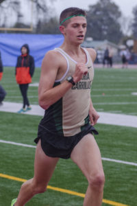 Athlete prepares for pole vault on a track with others watching.