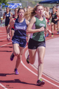 Athlete prepares for pole vault on a track with others watching.