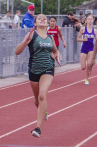 Athlete prepares for pole vault on a track with others watching.