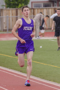 Athlete prepares for pole vault on a track with others watching.