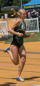 Athlete prepares for pole vault on a track with others watching.