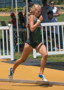 Athlete prepares for pole vault on a track with others watching.