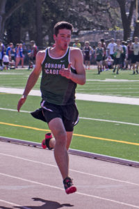 Athlete prepares for pole vault on a track with others watching.