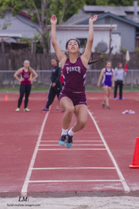 Athlete prepares for pole vault on a track with others watching.