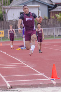 Athlete prepares for pole vault on a track with others watching.