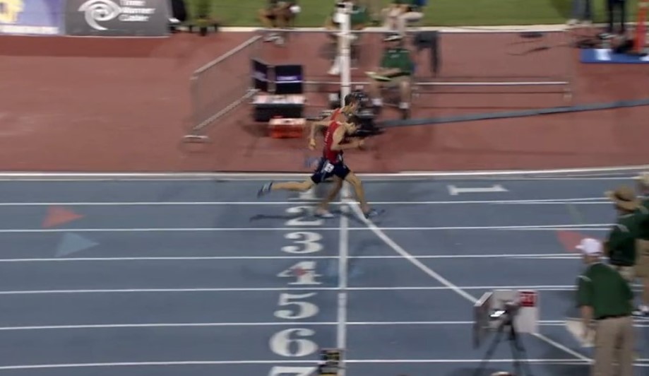 Athlete prepares for pole vault on a track with others watching.