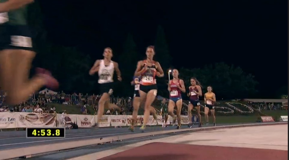 Athlete prepares for pole vault on a track with others watching.