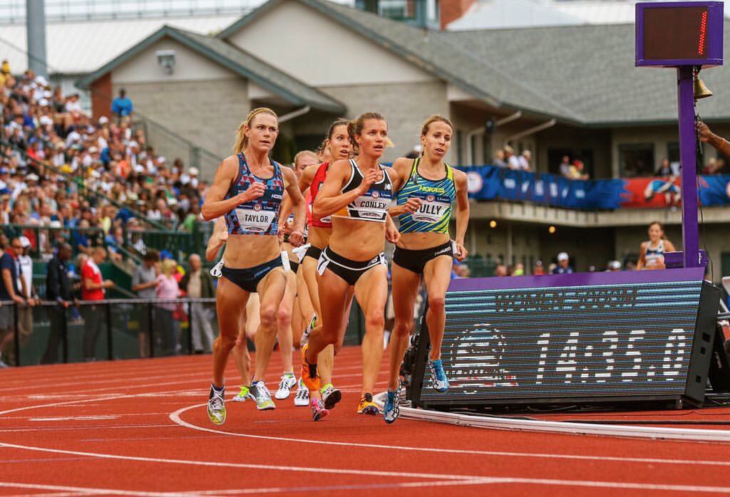Athlete prepares for pole vault on a track with others watching.