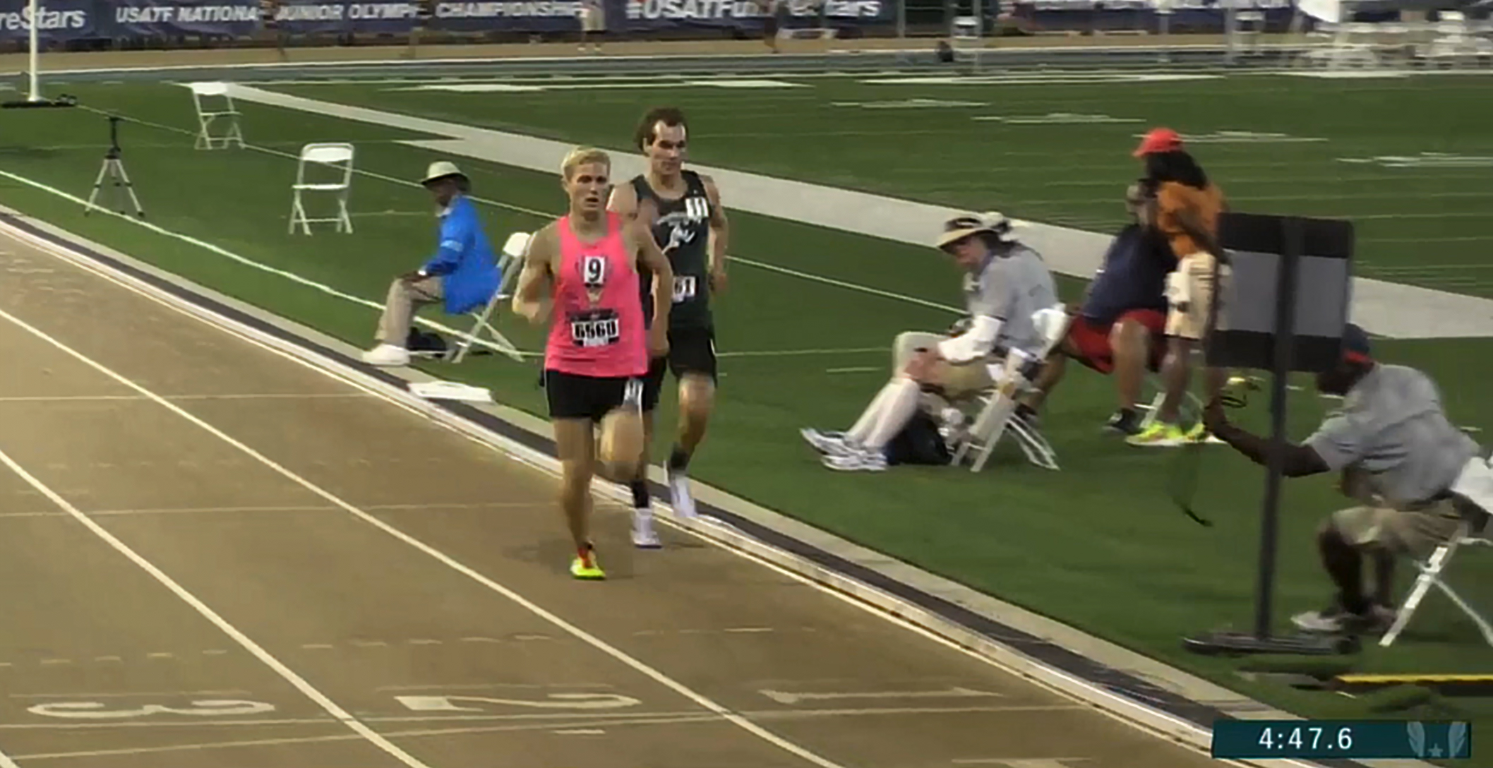Athlete prepares for pole vault on a track with others watching.