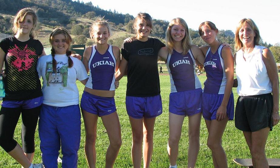 Athlete prepares for pole vault on a track with others watching.
