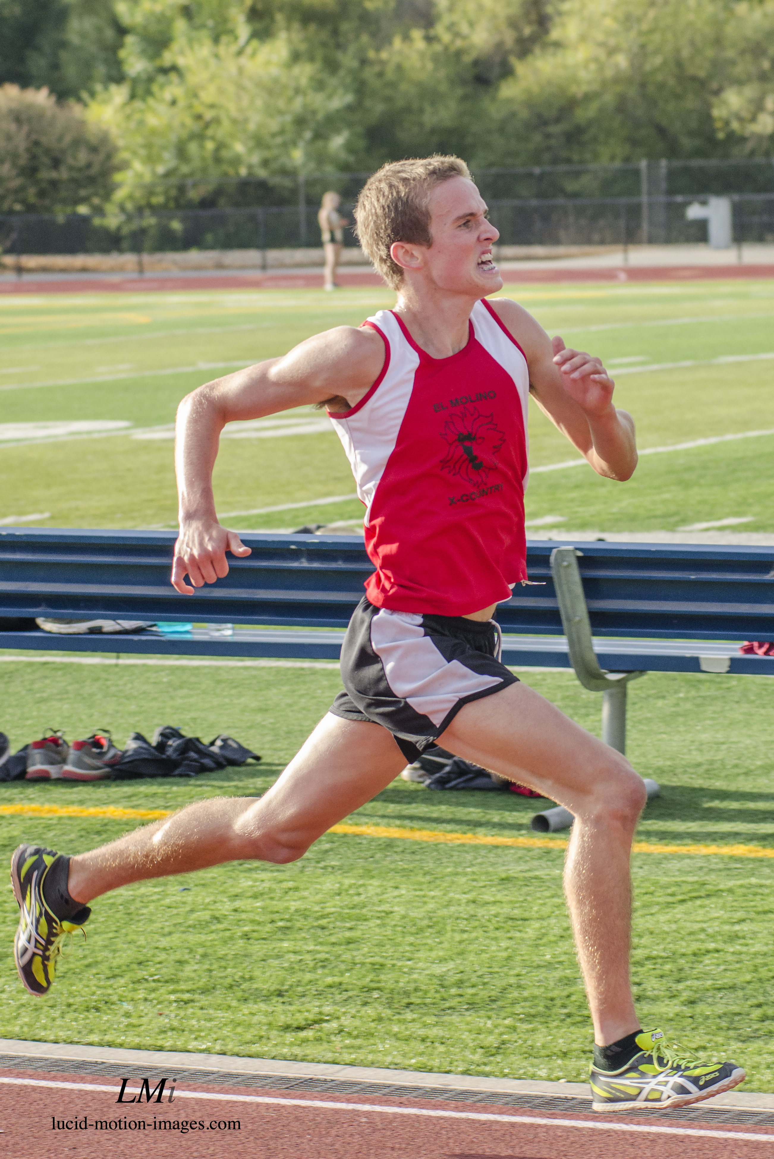 Athlete prepares for pole vault on a track with others watching.