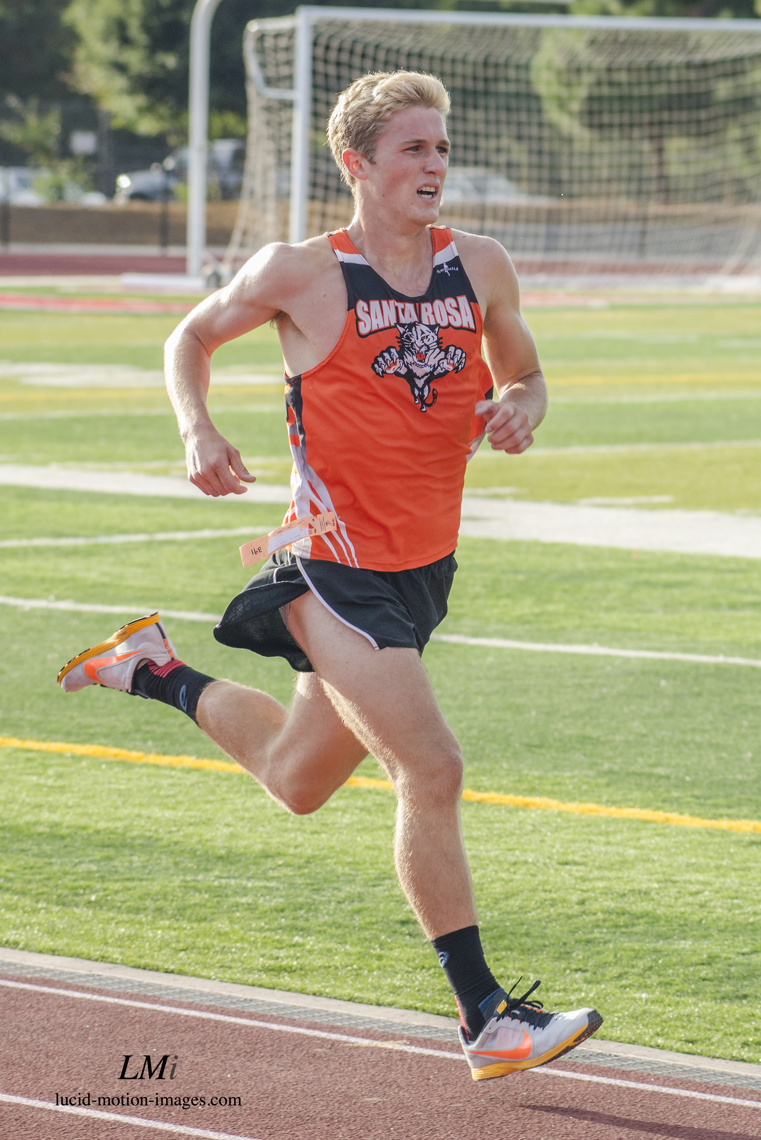 Athlete prepares for pole vault on a track with others watching.