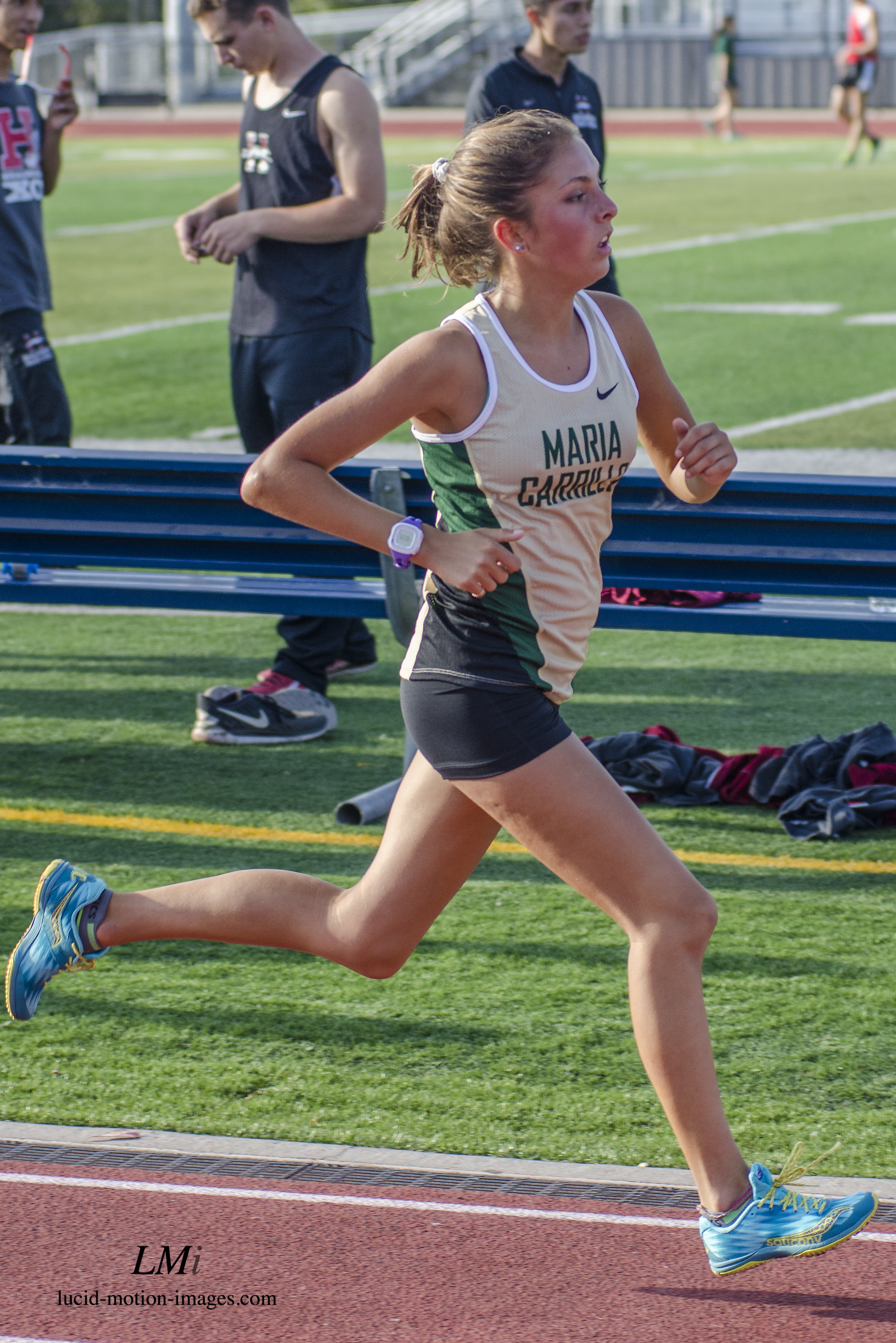 Athlete prepares for pole vault on a track with others watching.