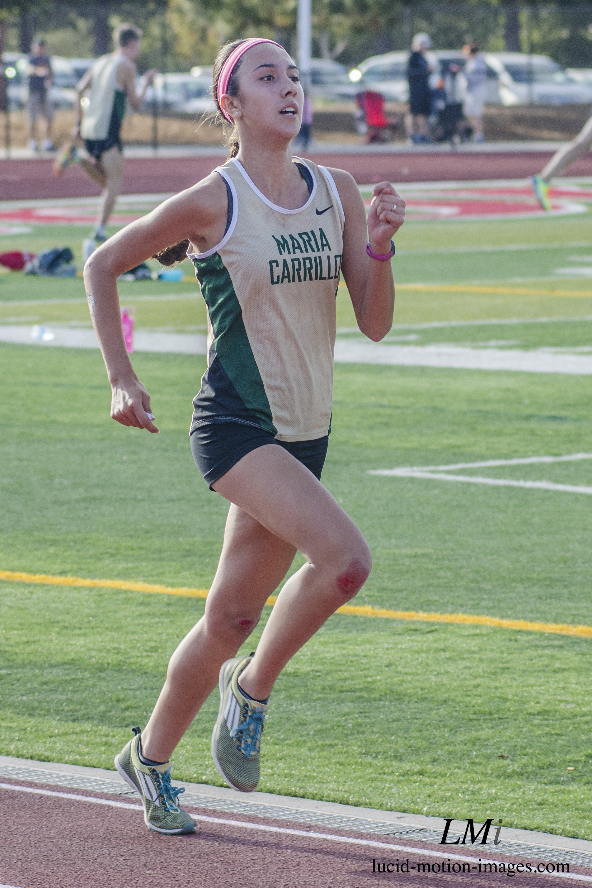 Athlete prepares for pole vault on a track with others watching.
