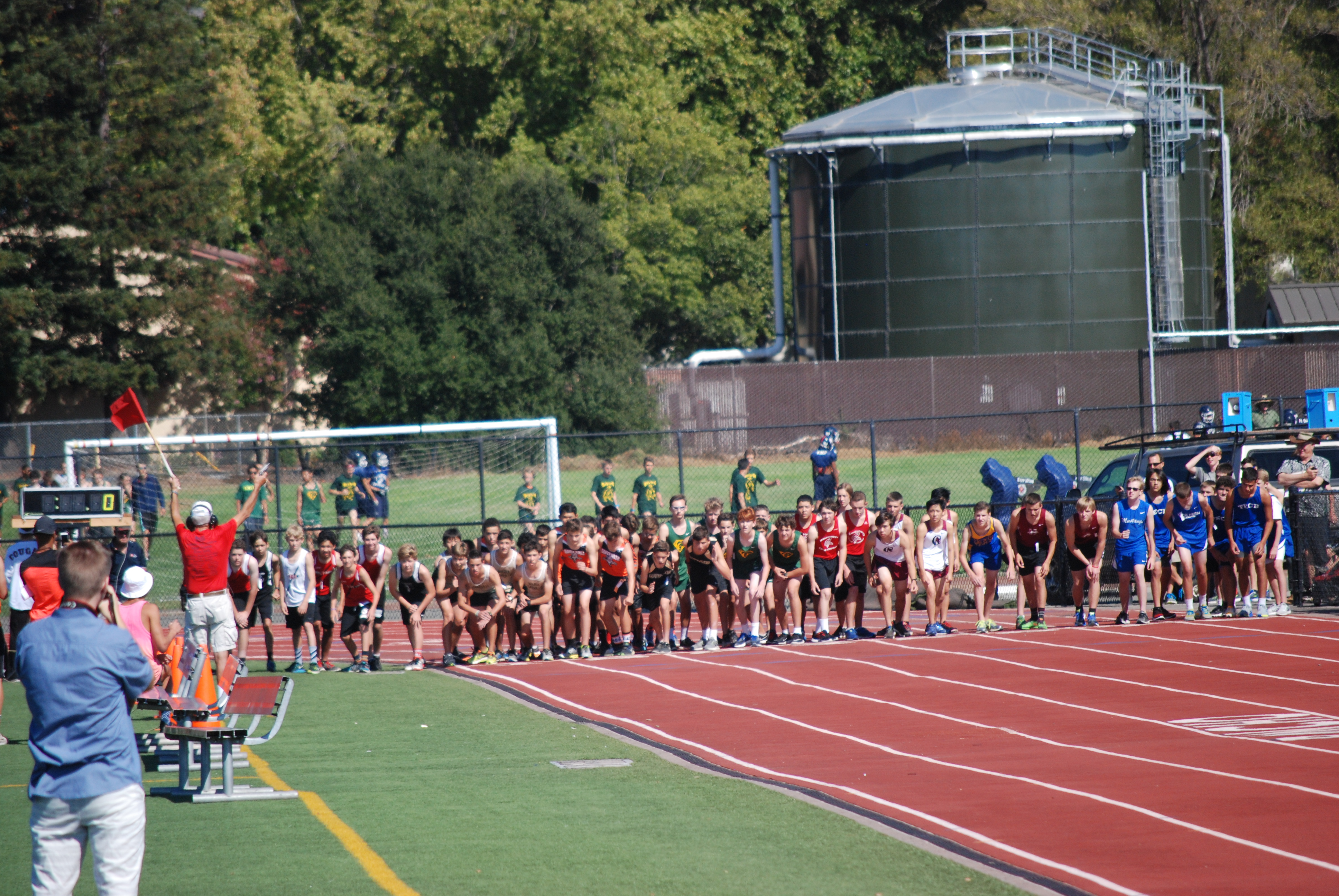 Athlete prepares for pole vault on a track with others watching.