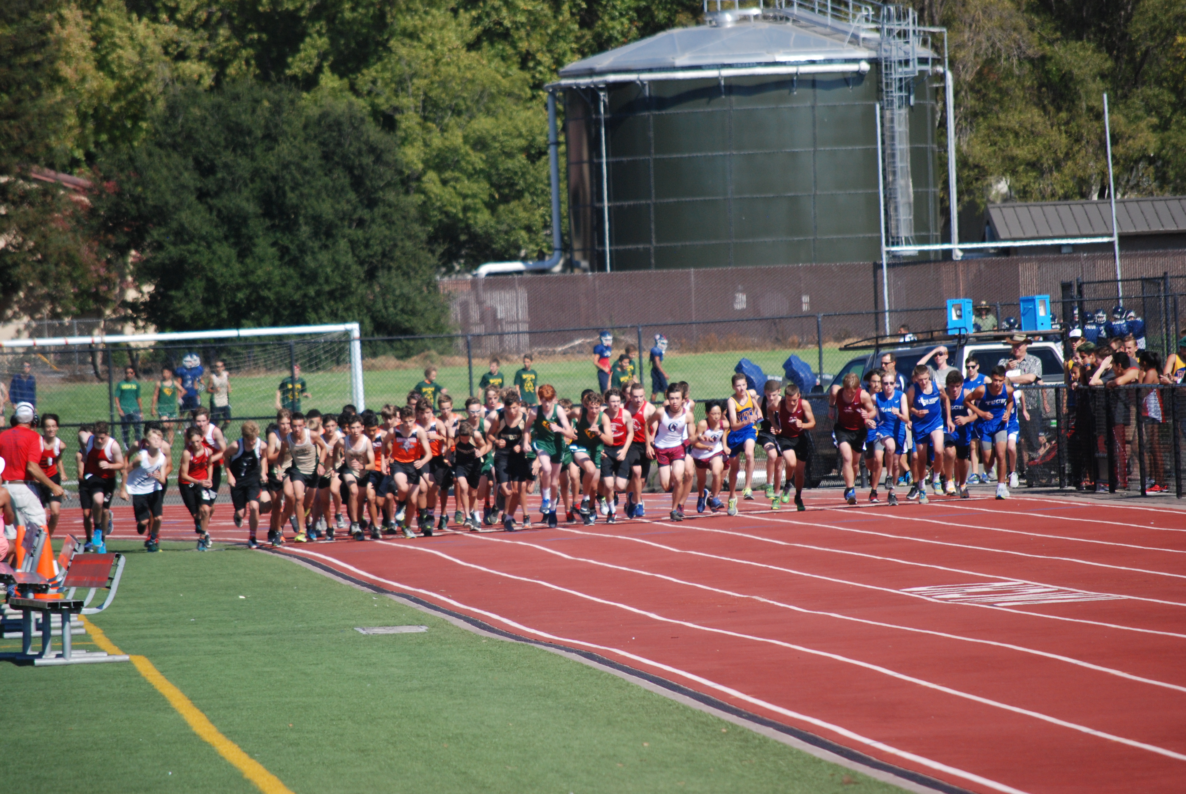 Athlete prepares for pole vault on a track with others watching.