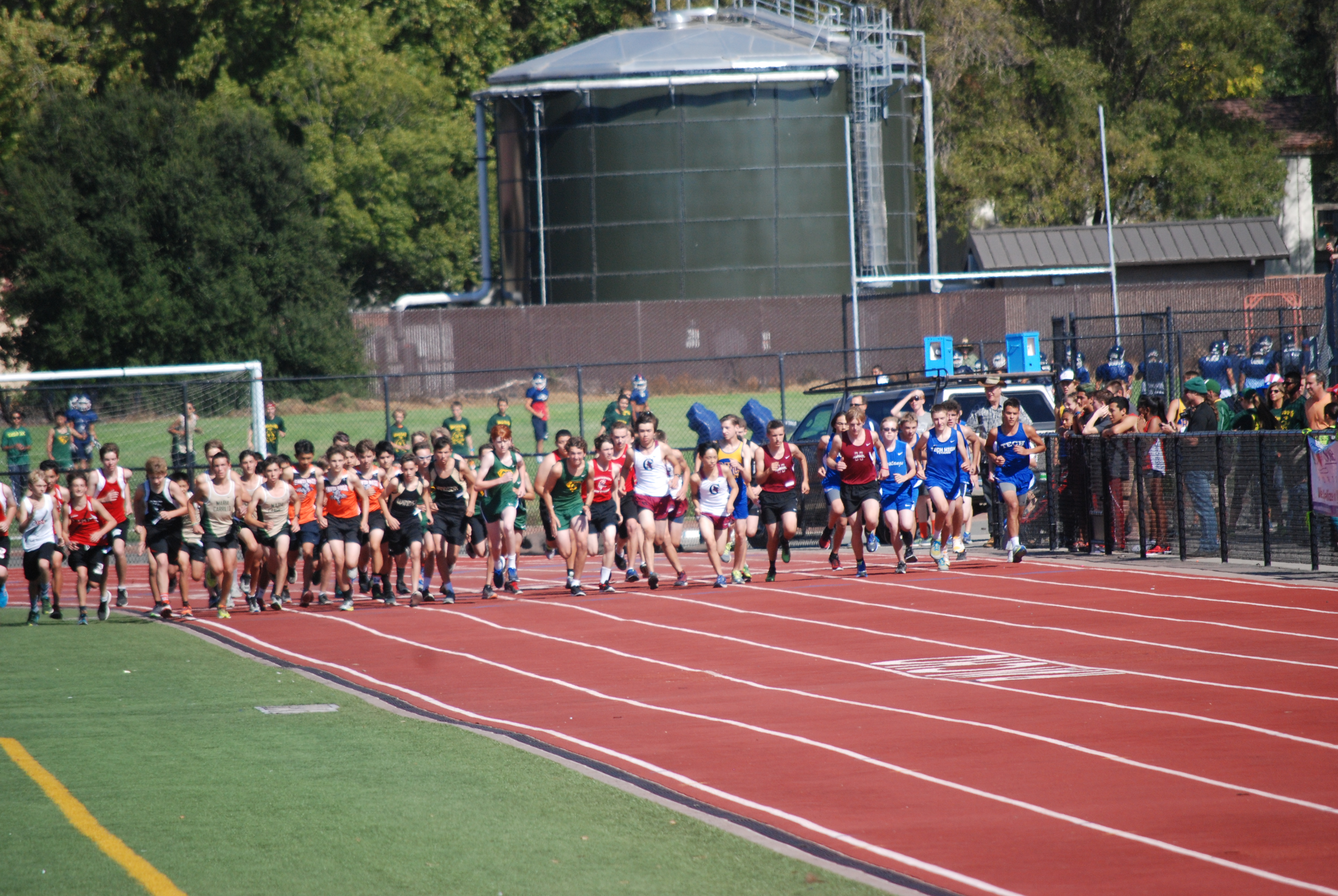 Athlete prepares for pole vault on a track with others watching.