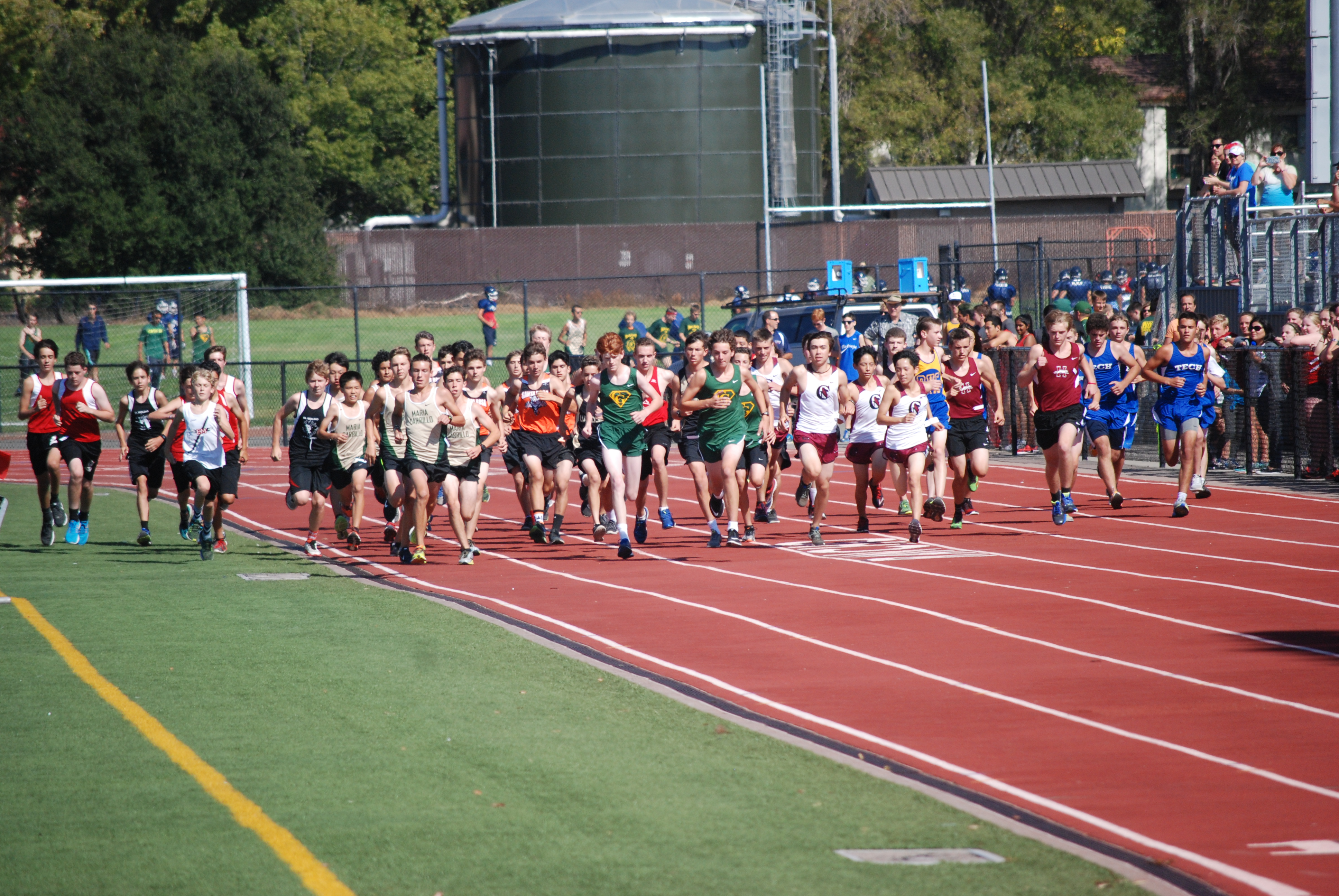 Athlete prepares for pole vault on a track with others watching.