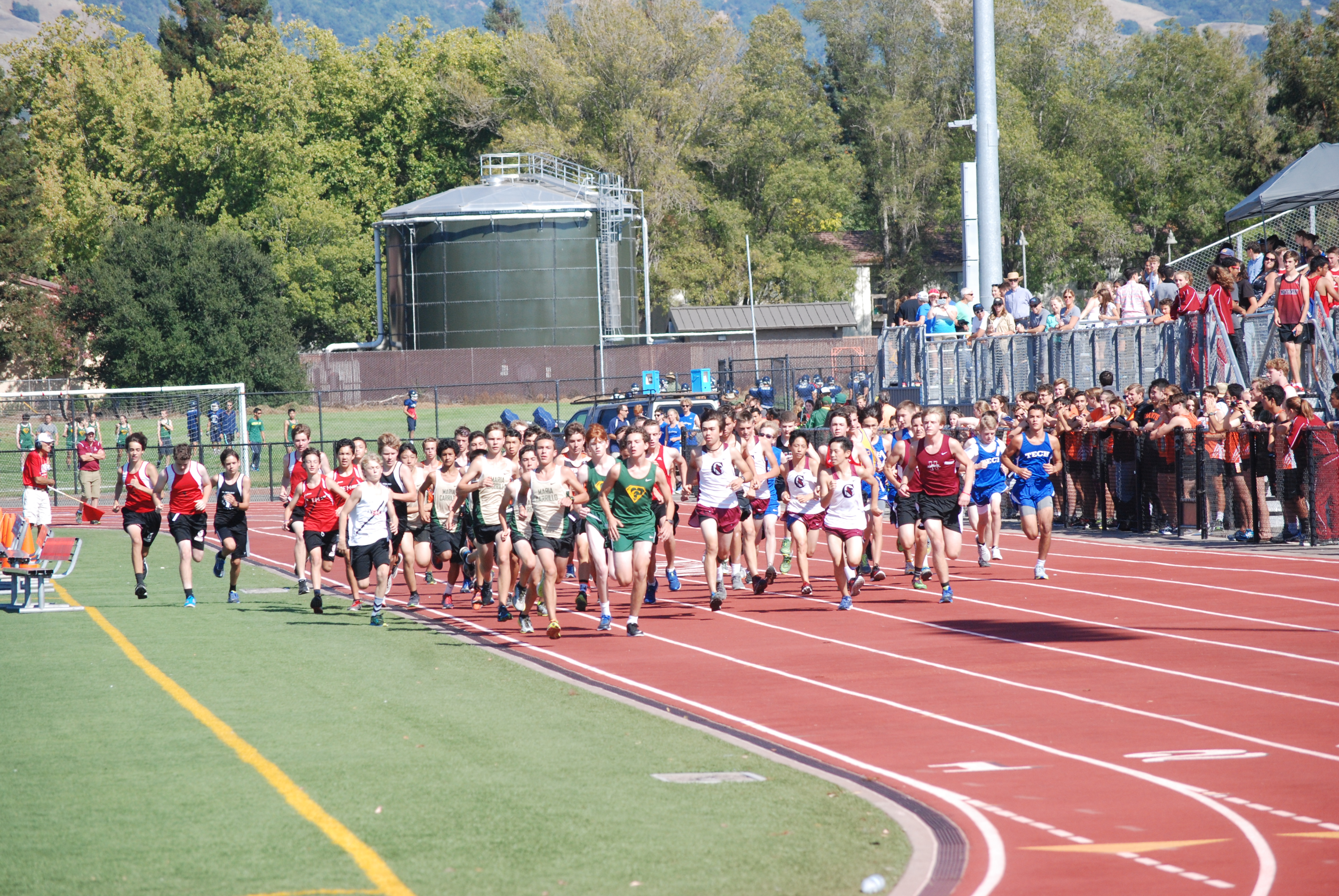 Athlete prepares for pole vault on a track with others watching.