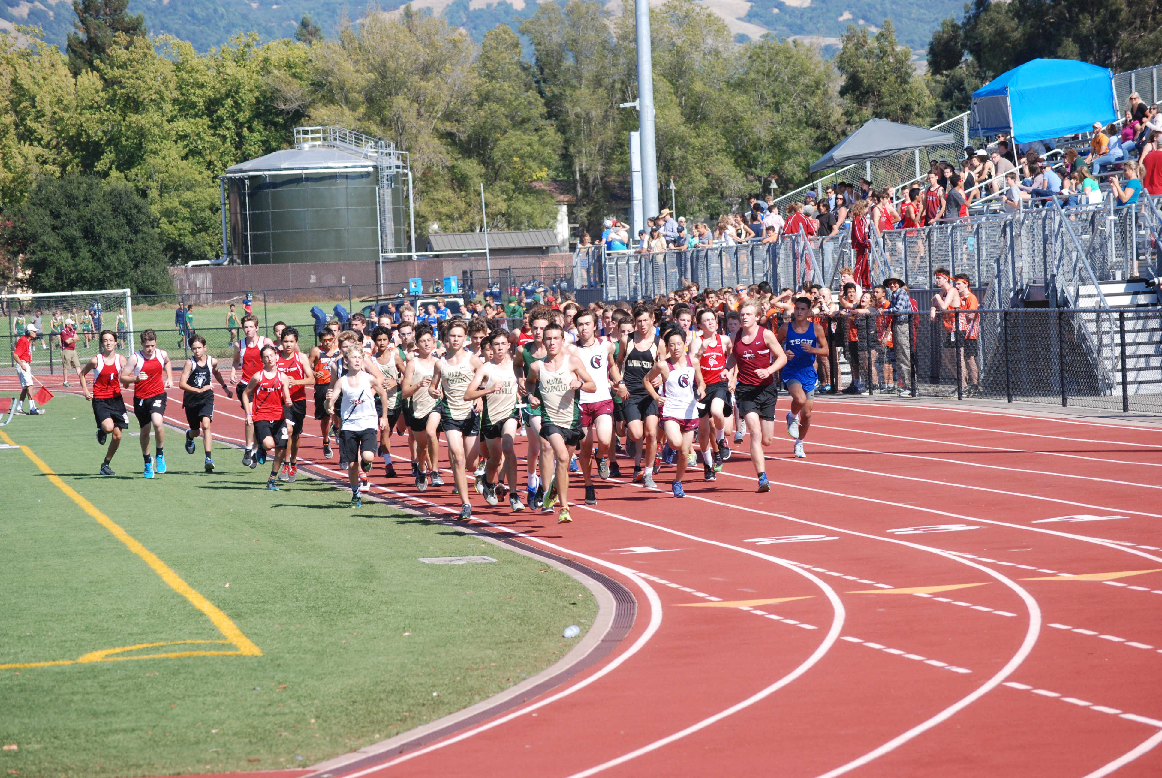 Athlete prepares for pole vault on a track with others watching.