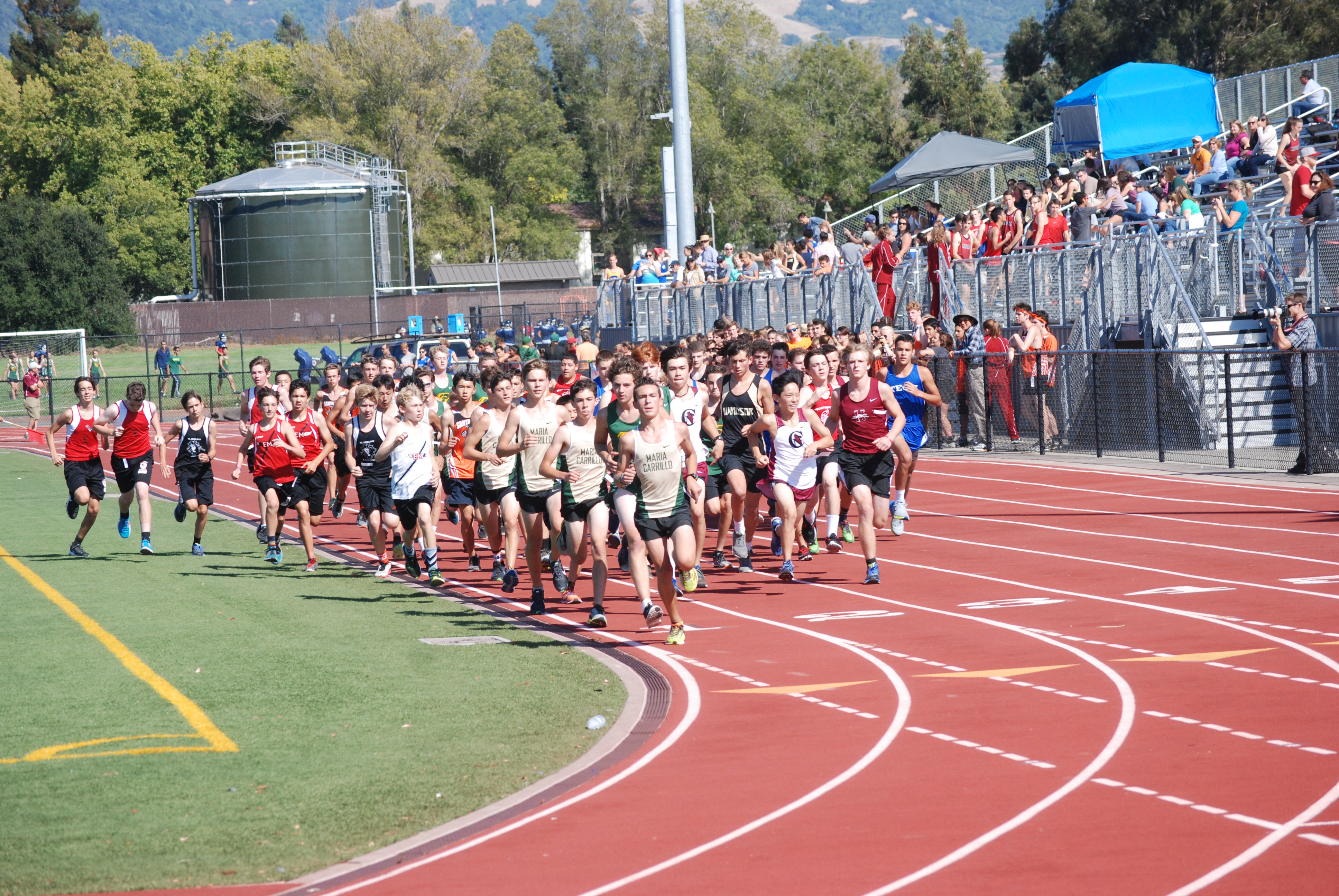 Athlete prepares for pole vault on a track with others watching.