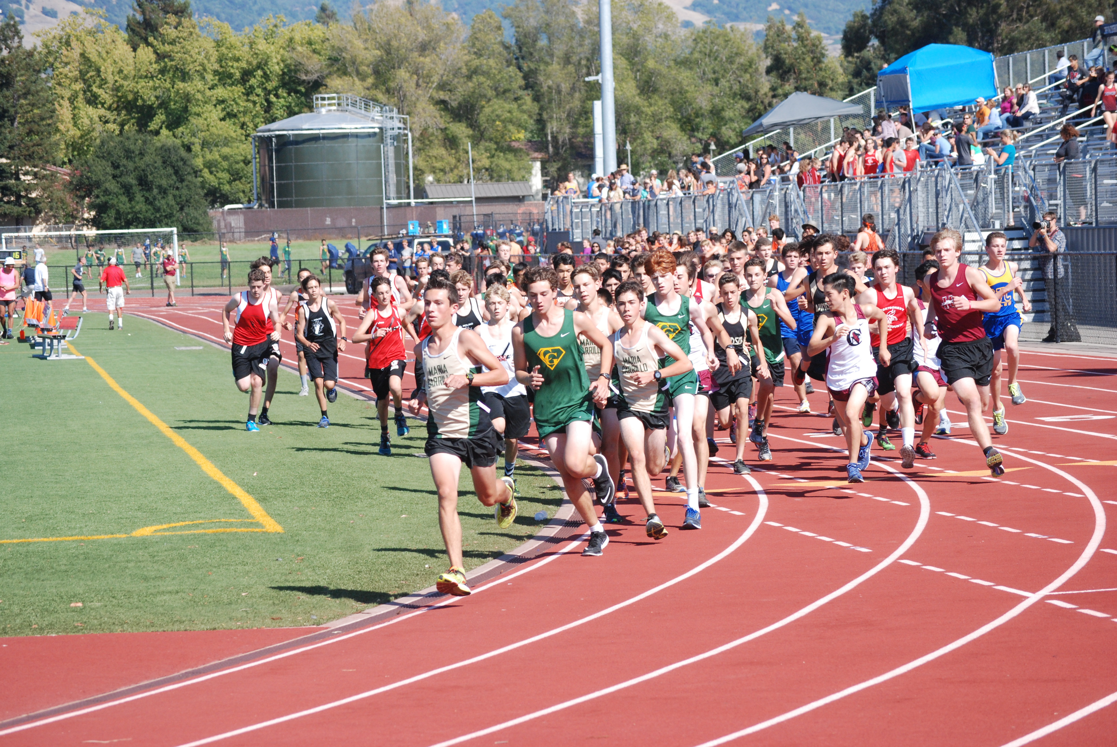 Athlete prepares for pole vault on a track with others watching.